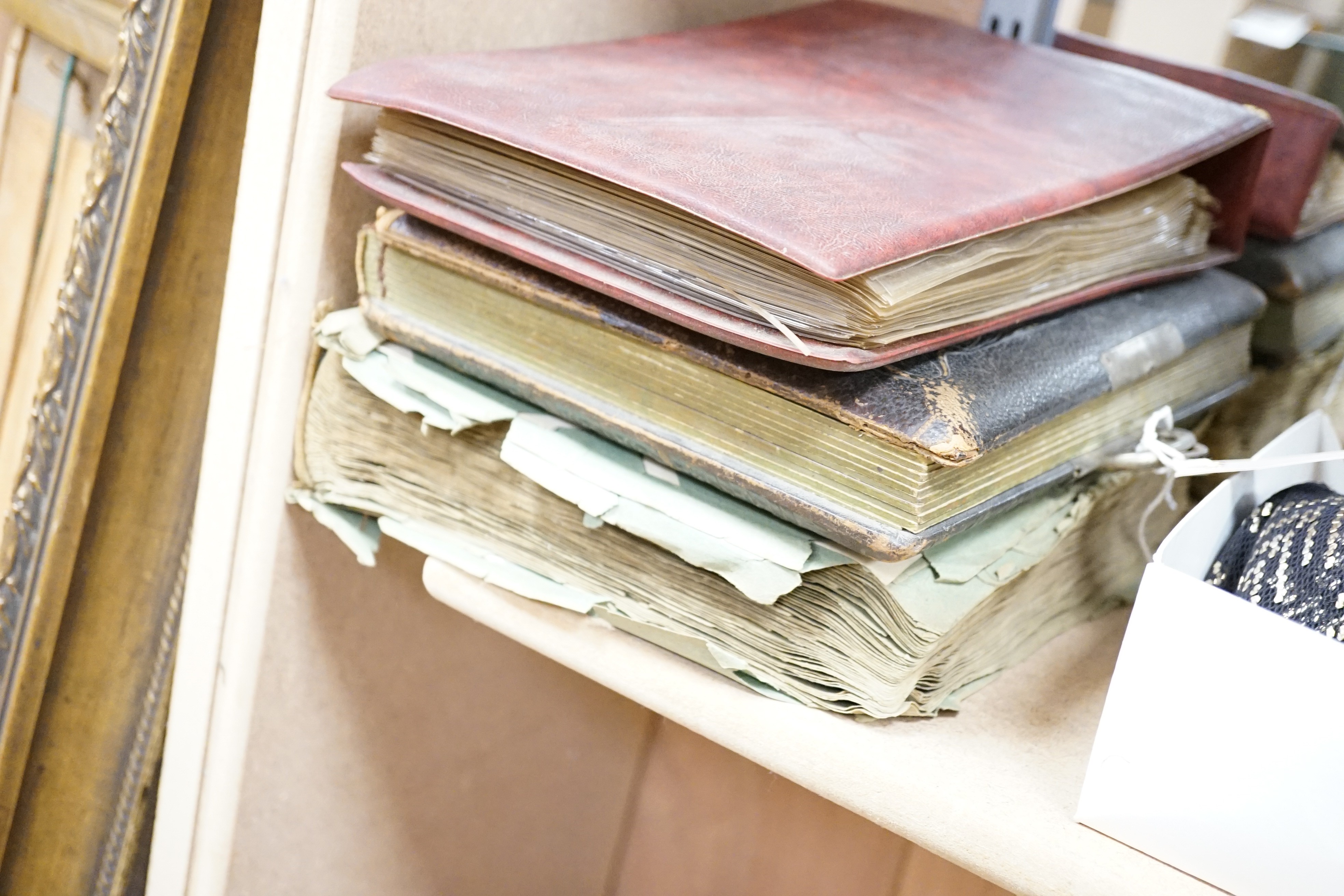 An early 20th century postcard collection in two albums and an empty late Victorian leather photo album
